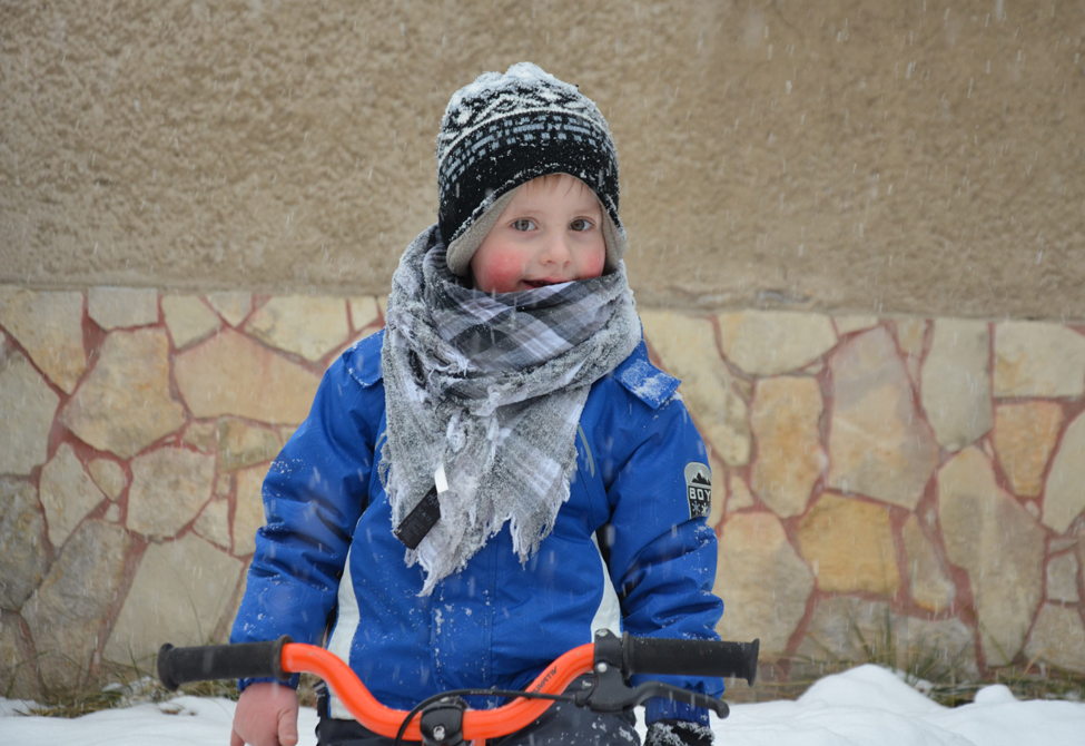 Kind im Schnee mit Fahrrad